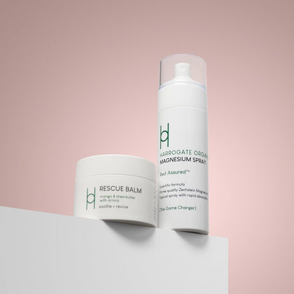 Magnesium Spray & Rescue Balm are shown against a pink background, featuring minimalist white and green packaging designed to help relieve muscle pain.