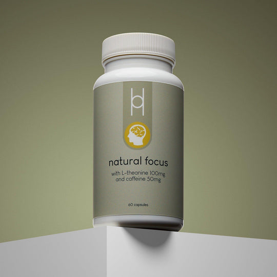 A minimalist white bottle of Natural Focus with L-Theanine 100mg and Caffeine 50mg, containing 60 capsules for mental clarity, sits on a white pedestal against a soft green gradient background.