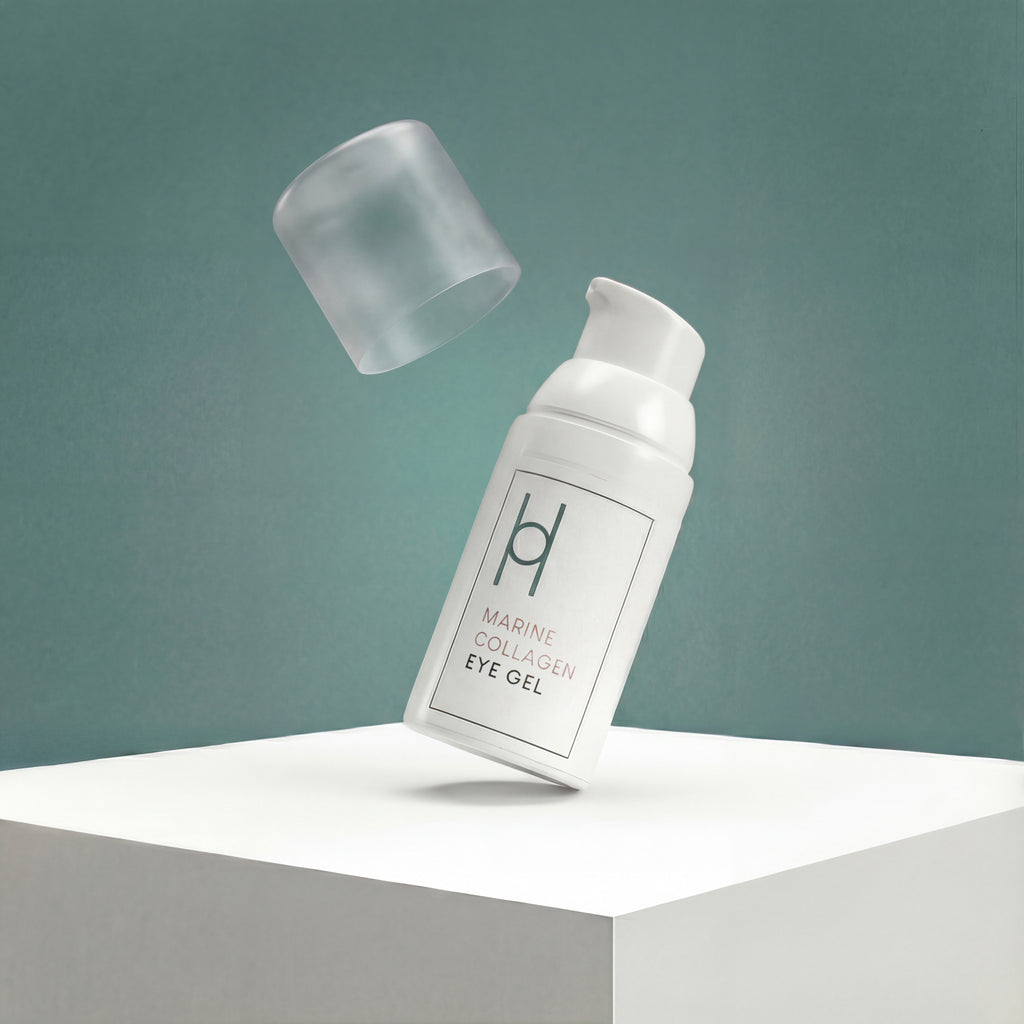 A white bottle of Marine Collagen Eye Gel with Hyaluronic Acid, Avocado Oil & Green Tea Extract (30ml) stands on a white platform. Its translucent cap floats above, highlighting its minimalist design against a muted teal background.