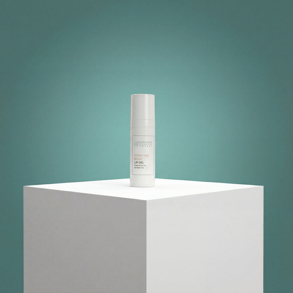 A white bottle of Hydration Boost Lip Gel (10ml) with a pump top stands on a white pedestal against a teal gradient background, its minimalistic label highlighting fuller, hydrated lips in an advanced, stylish cylindrical design.