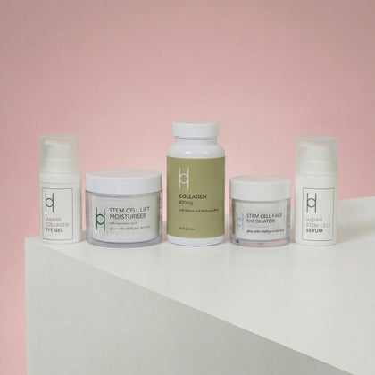 The Age Defying Skincare Set | Complete Anti-Ageing Gift Collection features five white minimalist containers with a collagen supplement, moisturiser, face exfoliator, eye gel, and serum on a white surface against a pink background.