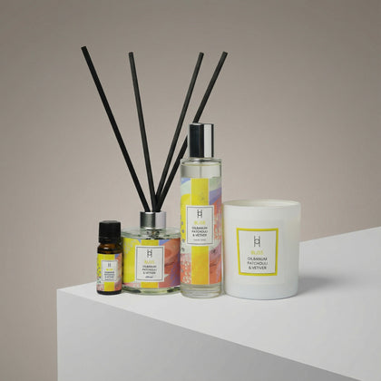 The Deluxe Bliss Home Collection | Complete Aromatherapy Gift Set features an essential oil bottle, reed diffuser, spray bottle, and the signature Bliss candle, all labeled "Bliss Oudlamum Patchouli & Vetiver," displayed on a white surface.