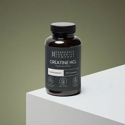 A dark bottle labeled Creatine HCL Supplement - 1500mg Serving - 30 Day Supply - 90 Capsules sits on a white surface against a muted green background. The label emphasizes its vegan and natural qualities as a gym supplement.