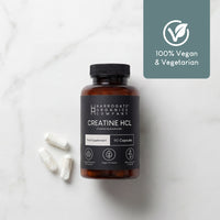 A bottle of Creatine HCL Supplement (1500mg, 90 capsules, 30 day supply) sits on a light surface with three white capsules and a label showing "100% Vegan & Vegetarian" alongside a leaf-checkmark icon.