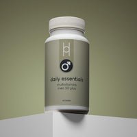 A bottle of Daily Essentials: Multivitamins for Men 50+ stands on a light surface against a gradient olive background. The minimalist label features a male gender symbol and clear text, highlighting immune-supporting vitamins and minerals.