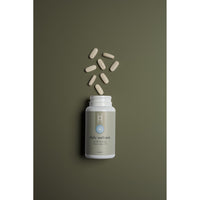 A white bottle labeled "Daily Wellness: Multivitamins for Men Under 50" rests on an olive green background with the cap off, and several beige tablets spill out in an arc above it.