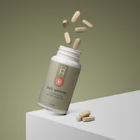 A tilted bottle of Daily Wellness: Multivitamins for Women Under 50 spills beige tablets onto a white surface. The scene is set against a gradient green background, highlighting its immune function and energy support benefits.
