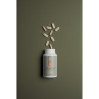 A white bottle labeled "Daily Wellness: Multivitamins for Women Under 50" with beige capsules spilling out sits on an olive green background. The minimalist label features a red flower-like logo and promotes essential vitamins and minerals for energy support.
