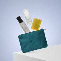 A Deep Sleep Gift Set – Magnesium Spray, Pillow Mist, Soap & Travel Pouch, featuring a bottle of magnesium spray, calming pillow mist, and a bar of soap hovering above a teal zippered pouch embroidered with the words Sleep. Deep. Sleep.