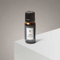 A 10ml amber bottle of Winter Wonderland Essential Oil—Citrus Orange & Cedar—rests on a white surface against a gray background. Its luxury minimalist label and black cap evoke an inviting winter scent.