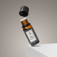 A 10ml Winter Wonderland Essential Oil bottle—Citrus Orange & Cedar, brown glass with a black cap—floats above a white surface against a neutral background, perfect for bringing cozy winter scent to your space.