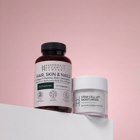 A bundle featuring the Hair, Skin & Nails Complex and a 50ml Stem Cell Lift Moisturiser enriched with Hyaluronic Acid is displayed on a white surface against a pink background.
