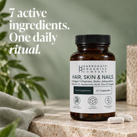A bottle of Hair, Skin & Nails Complex rests on a stone surface, accompanied by two capsules. Beside the bottle, text reads: 7 active ingredients. One daily ritual for healthier hair, skin, and nails with this advanced beauty supplement.