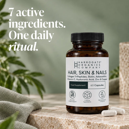 A bottle of Hair, Skin & Nails Complex rests on a stone surface, accompanied by two capsules. Beside the bottle, text reads: 7 active ingredients. One daily ritual for healthier hair, skin, and nails with this advanced beauty supplement.