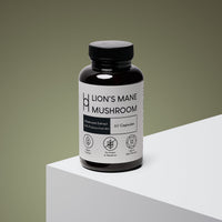 A dark brown bottle labeled "Lion's Mane Mushroom Supplement 800mg Per Serving – 30 Day Supply – 60 Capsules" sits on a white surface. The label notes vegan, no grains or mycelium, beta-glucans, and cognitive health support.