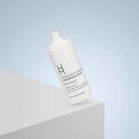 A white bottle of Harrogate Organics Magnesium Spray labeled Rest Assured is tilted on a white surface with a light blue gradient background—perfect to pair with your Best Sellers Trio for ultimate relaxation.