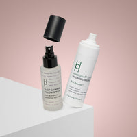 Two spray bottles of Magnesium Spray and Pillow Mist are displayed on a white surface with a pink background, one with its cap appearing to float above it—ideal aids for restful sleep.