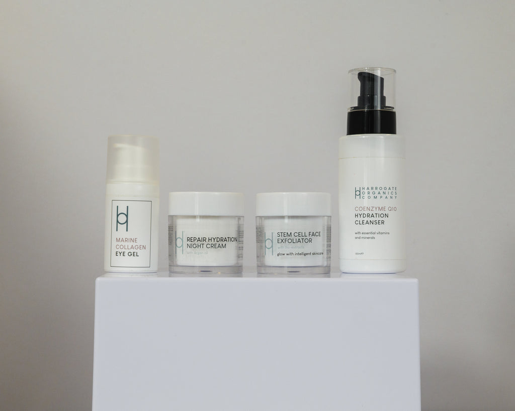 Four skincare products in white containers sit on a white platform: Marine Collagen Eye Gel, Men's Skin Reset Hydration Night Cream, Stem Cell Face Exfoliator, and Cognitive CBD Hydration Cleanser.