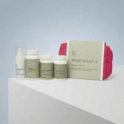 The Meno Relief - Menopause Kit, featuring bottles, a pump dispenser, and a box labeled "Meno Relief + Support Pack," is displayed on a white geometric surface with a pink pouch placed behind the box.