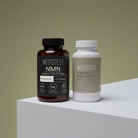 The NMN & Turmeric & Black Pepper Supplement Bundle from Harrogate Organics Company is pictured here, featuring two bottles on a light-colored surface: one brown bottle labeled with NMN plus magnesium, zinc, and collagen, and a white bottle labeled Turmeric & Black Pepper High Strength.