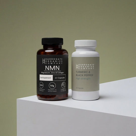 The NMN & Turmeric & Black Pepper Supplement Bundle from Harrogate Organics Company is pictured here, featuring two bottles on a light-colored surface: one brown bottle labeled with NMN plus magnesium, zinc, and collagen, and a white bottle labeled Turmeric & Black Pepper High Strength.