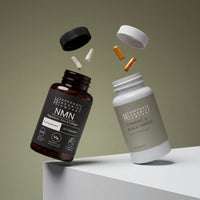 Two bottles from the NMN & Turmeric & Black Pepper Supplement Bundle are suspended at angles, with capsules and tablets floating between them. The neutral background features soft shadows.