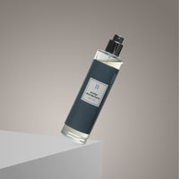 A clear spray bottle labeled Winter Wonderland Mist with a black cap and dark label leans diagonally on a white surface, evoking a winter scent against a gradient beige background.