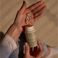 A person holds Ashwagandha capsules in one hand and an open bottle labeled "Multipack - Natural Ashwagandha (4 Month Supply)" in the other, emphasizing its popular use for immune support against a neutral background.