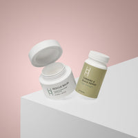 The Turmeric & Black Pepper Supplement + Rescue Balm Bundle sits on a white geometric surface with a pink gradient backdrop—curated to help reduce inflammation.