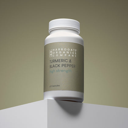 A white bottle labeled Turmeric & Black Pepper Supplement - High Strength 2500mg Per Serving, 60 capsules for a 30-day supply, sits on a white platform against a neutral background.