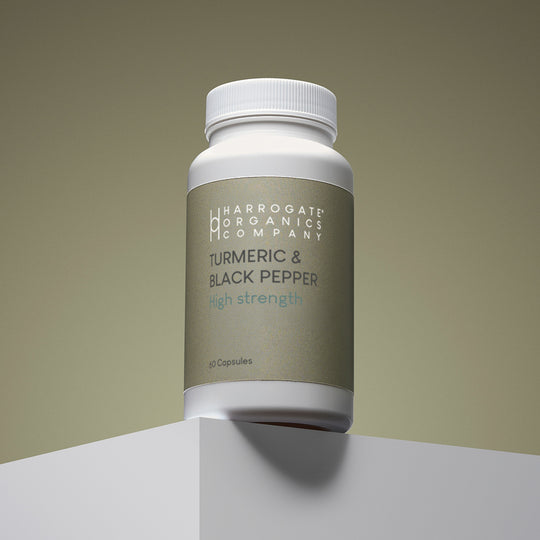 A white bottle labeled Turmeric & Black Pepper Supplement - High Strength 2500mg Per Serving, 60 capsules for a 30-day supply, sits on a white platform against a neutral background.