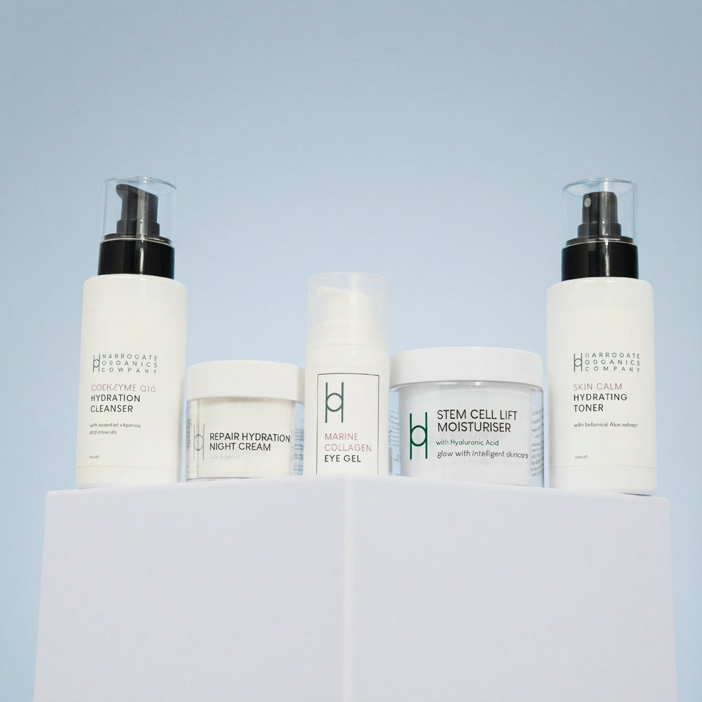 The Ultimate Men's Skincare Routine from Harrogate Organics Co. is displayed on a white platform with a light blue background, featuring cleanser, night cream, eye gel, moisturizer, and hydrating toner for a complete regimen.