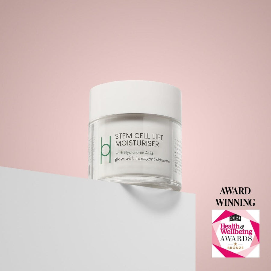 A jar of Stem Cell Lift: Hyaluronic Acid Face Cream with hibiscus stem cells sits on a white surface against a pink background. A 2021 Health & Wellbeing Awards Bronze badge and "Award Winning" text appear in the bottom right corner.