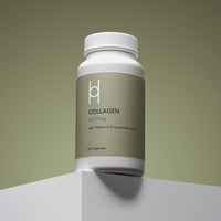 A white bottle of Marine Collagen 450mg with Vitamin C & Hyaluronic Acid Supplement (60 capsules, 60-day supply) is placed on a white platform against a muted green background.