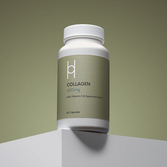 A white bottle of Marine Collagen 450mg with Vitamin C & Hyaluronic Acid Supplement (60 capsules, 60-day supply) is placed on a white platform against a muted green background.