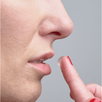 A close-up shows a person about to apply Hydration Boost Lip Gel (10ml) for fuller, hydrated lips with their finger. Their red-painted fingernails are visible near their nose and mouth.