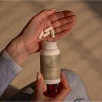 A person holds a bottle labeled "Marine Collagen 450mg with Vitamin C & Hyaluronic Acid" and white capsules, highlighting this 60-capsule supplement that offers a vitamin C boost and hyaluronic acid for added support.